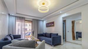 A modern living room with a sofa, armchairs, a coffee table, and a large mirror. - Stylish apartment with swimming pool, sauna and hammam in central Marrakech   (Marrakech)