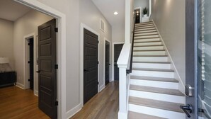 A modern interior with a staircase, wooden flooring, and dark doors.