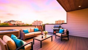 A rooftop patio with outdoor furniture, a grill, and a hot tub.