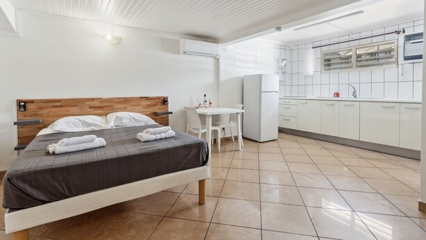 Een moderne hotelkamer met een bed, een klein bureau en een kitchenette.