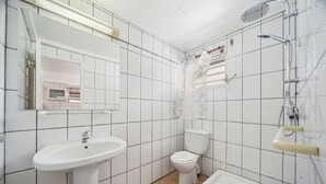 A bathroom with white tiles, a sink, toilet, and a bathtub. - Studio 1-Anthurium - A 7min de la plage (Les Trois-Îlets)