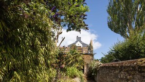 A stone pathway leading to a building with a gabled roof and a chimney. - La Petite Mouette - Maison au port de Dahouët (Pléneuf-Val-André)