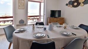 A dining area with a table set for four, a television, and a decorative wall piece.