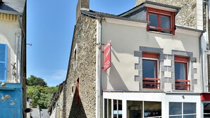 A building with a stone facade, a red sign, and multiple windows.