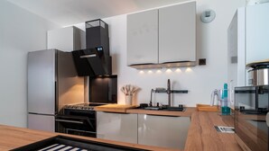 Une cuisine moderne dotée d’appareils électroménagers en acier inoxydable, d’un plan de travail en bois et d’un four encastré.