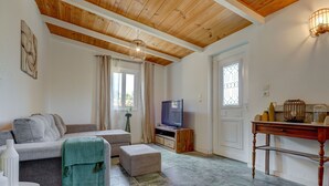 Ein Wohnzimmer mit Sofa, Hocker, Fernseher und einem Tisch mit Dekoration.