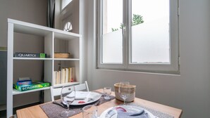 Ein Essbereich mit einem Tisch für zwei Personen, einem Bücherregal mit Gesellschaftsspielen und einem Fenster mit Blick.