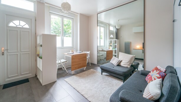 Ein modernes Wohnzimmer mit einem grauen Sofa, einem Holztisch und einem großen Spiegel.