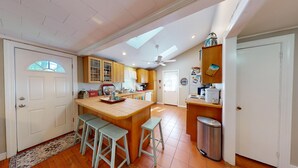 A spacious kitchen with a central island, wooden cabinets, and a ceiling fan. - "Charming 2-Bedroom Home in Narragansett with Private Beach Access and WiFi" (Narragansett)