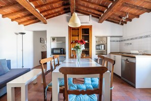 Un coin repas avec une table en bois, des chaises et un vase de fleurs.