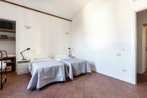 Une chambre avec deux lits, un bureau, une lampe et une étagère avec des boîtes.