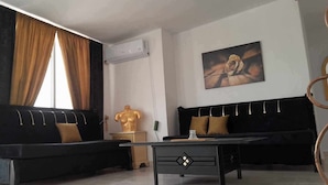 A modern living room with two black sofas, a glass coffee table, and a golden bust sculpture. - Dar Lella (Bizerte)