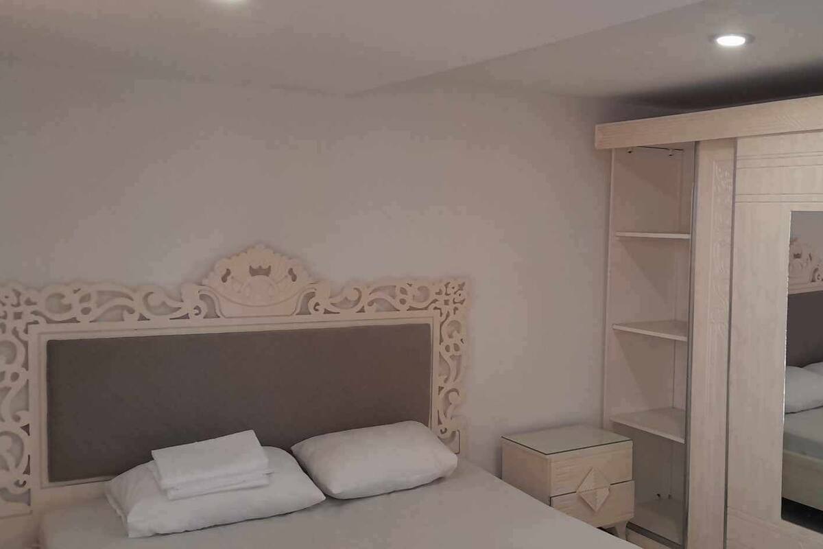 A bedroom with a bed, a nightstand, a wardrobe, and a mirror.