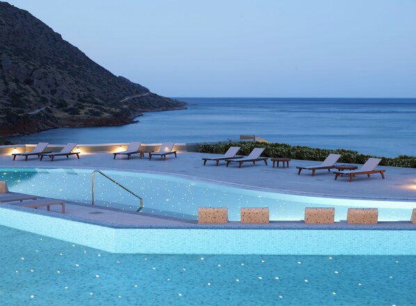 An infinity pool with lounge chairs and a view of the sea.