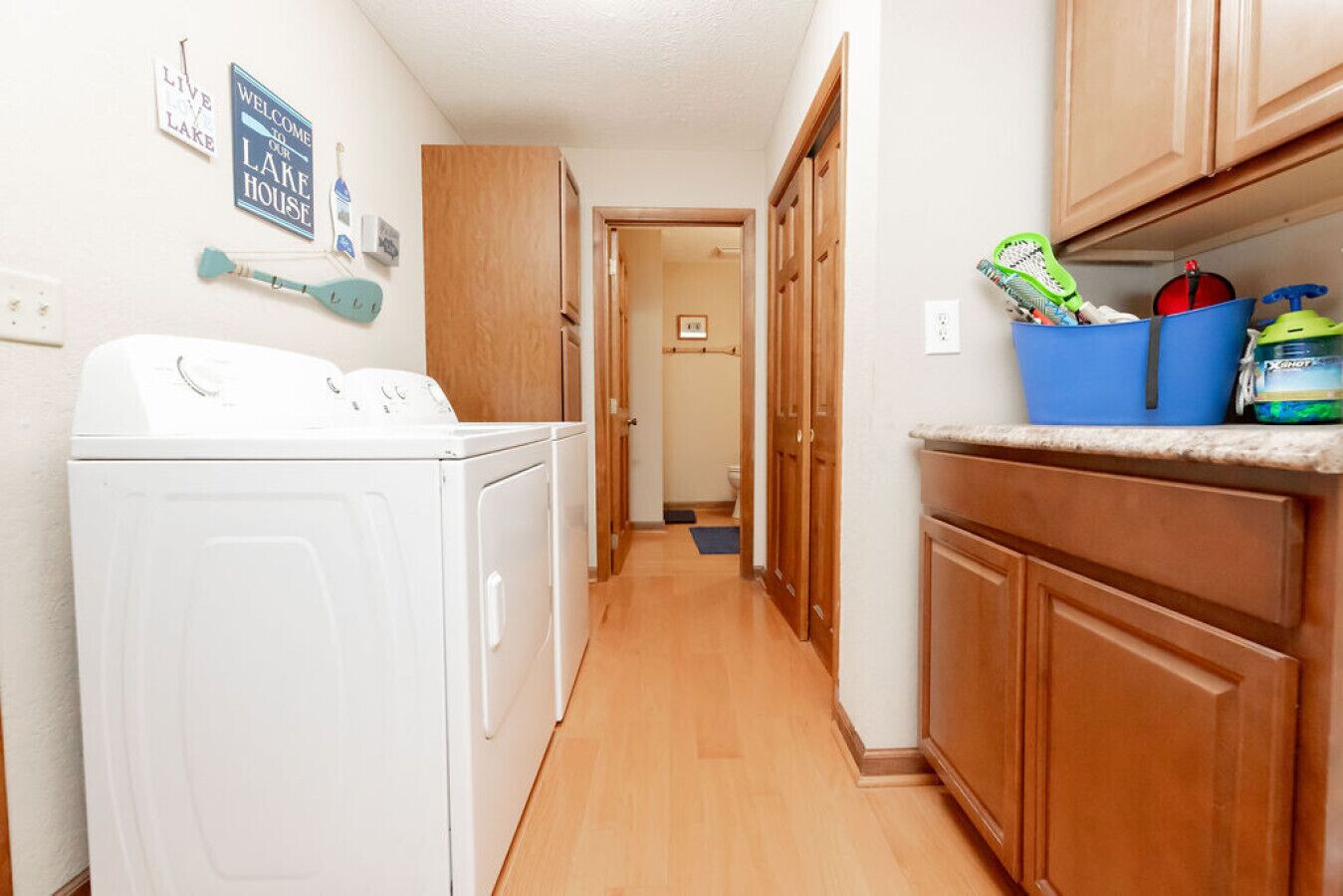 A laundry area with a washer and dryer, wooden cabinets, and a kitchen counter with cleaning supplies.