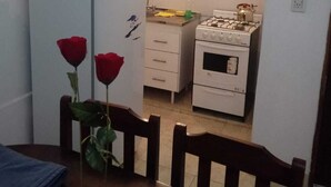 A compact kitchen with a refrigerator, stove, and sink. There are two red roses on the table. - DepartamentoLaCascada (Termas de Rio Hondo)