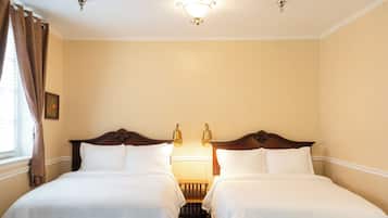 Una habitación de hotel con dos camas individuales, una mesita de noche, una pequeña mesa y una lámpara en el techo.