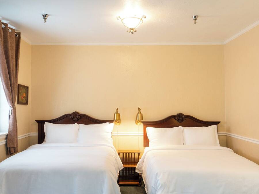 Una habitación de hotel con dos camas individuales, una mesita de noche, una pequeña mesa y una lámpara en el techo.
