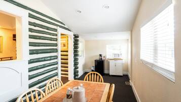 Cocina compacta con microondas, refrigerador y ventana con persianas.