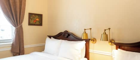 Ein Hotelzimmer mit einem Bett, zwei Nachttischlampen, einem Fenster mit Vorhängen und einem Bild an der Wand.