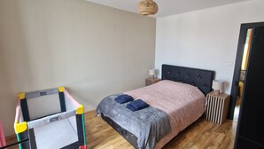 A bedroom with a bed, bedside tables, a wardrobe, and a hanging laundry rack. - Le P'tit Colin 1er (Pontarlier)