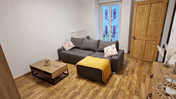 A cozy living room with a grey sofa, wooden coffee table, and a wooden door. - Le P'tit Colin 1er (Pontarlier)