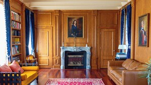 A room with a fireplace, a yellow sofa, a brown leather couch, and a bookshelf. - Florence Room at Chateau Herbe (Ashland)