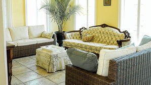 A room with a yellow wall, two wicker sofas, a potted plant, and a tiled floor. - Florence Room at Chateau Herbe (Ashland)