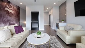 A modern living room with a white sofa, a round coffee table, and a ceiling fan. - Walk to West End | Rooftop Terrace + Deck (Nashville)