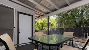 An outdoor patio with a glass-top table and four chairs, a door, and a wooden fence in the background. - In The Heart Of Downtown Boise! (Boise)