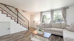 A living room with a staircase, a sofa, a coffee table, and a door. - In The Heart Of Downtown Boise! (Boise)