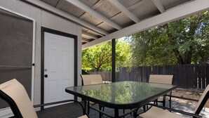 An outdoor patio with a glass-top table and four chairs, a door, and a wooden fence in the background. - 2 Condos, Minutes From Downtown, Parks, and Freeway! (Boise)