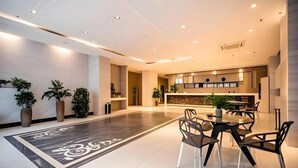 A modern hotel lobby with a central dining area, a reception desk, and potted plants. - Jiajie Boutique Hotel (Lingao Cultural Park Fulo Plaza Branch) (Lingao)
