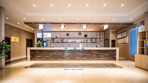A modern hotel lobby with a reception desk, a large plant, and a blue wall with shelves. - Jiajie Boutique Hotel (Lingao Cultural Park Fulo Plaza Branch) (Lingao)