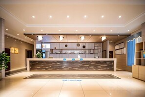 Zona de recepción de un hotel con mostrador de recepción, área de espera y un mostrador de atención al cliente.