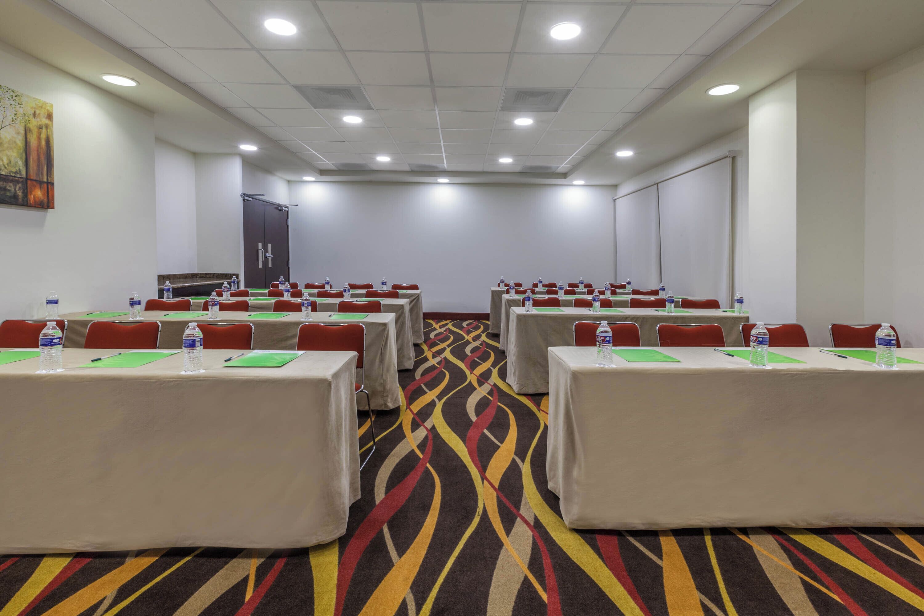 A conference room with tables, chairs, and a carpeted floor.