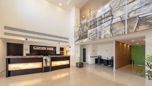 A hotel reception area with a modern design, including a reception desk, a large abstract painting, and a green wall. - Garden Park San Luis Potosí (San Luis Potosi)