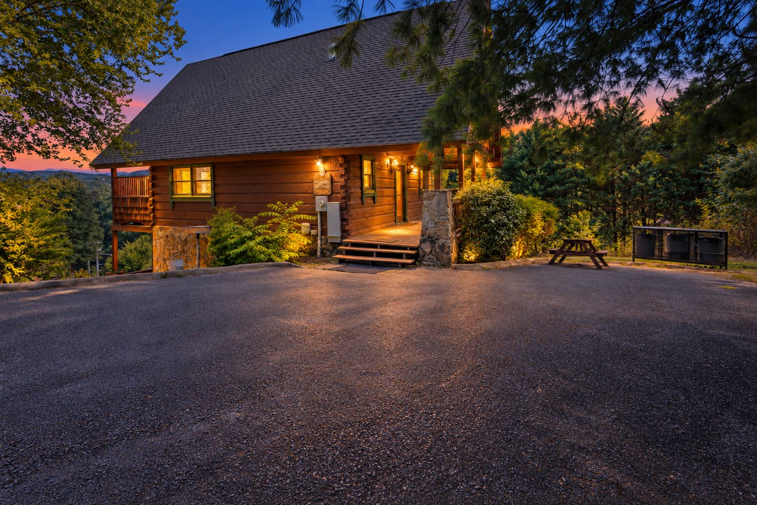 A wooden cabin with a stone foundation, a porch, and a picnic table.
