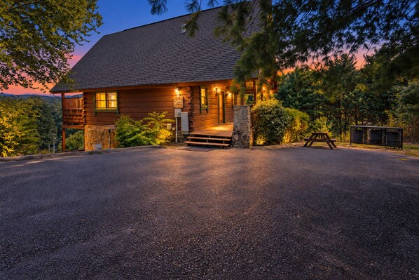 A wooden cabin with a stone foundation, a porch, and a picnic table.