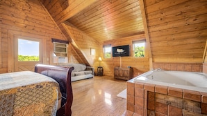 Una cabaña acogedora con interior de madera, un sofá, una cama, una chimenea y un jacuzzi.