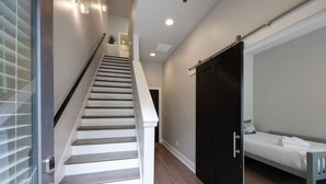 Una escalera que conduce a un dormitorio con una cama, un armario y una puerta.