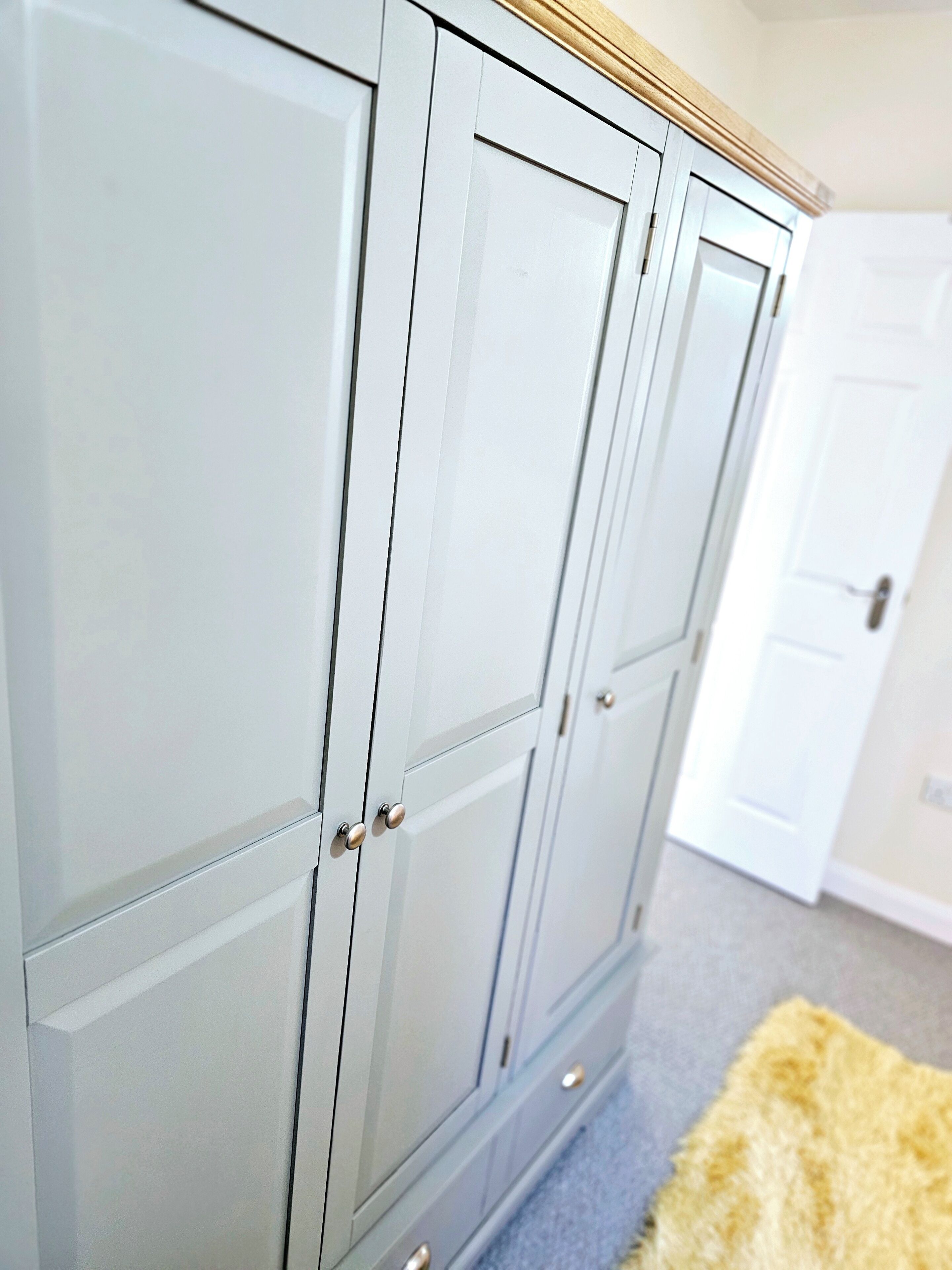 A set of white cabinets with silver handles and a wooden trim.