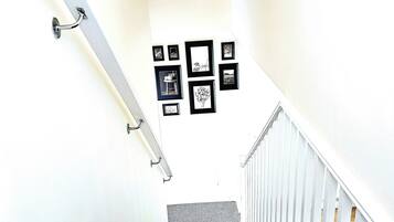 Un escalier mène à un bâtiment blanc dont le mur est orné d’une série de tableaux encadrés.