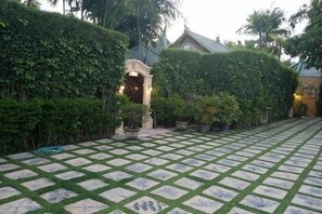 A paved courtyard with a tiled pattern, a small archway, and lush greenery. - Bali Emerald Villas (Bali)