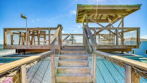 Eine Holztreppe führt zu einer überdachten Holzterrasse mit Metallgeländer.