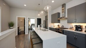 A modern kitchen with a central island, stainless steel appliances, and a bar seating area. - West End Luxe | Rooftop Deck + Skyline (Nashville)