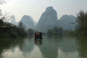 Ein Boot auf einem ruhigen Fluss, im Hintergrund Berge.