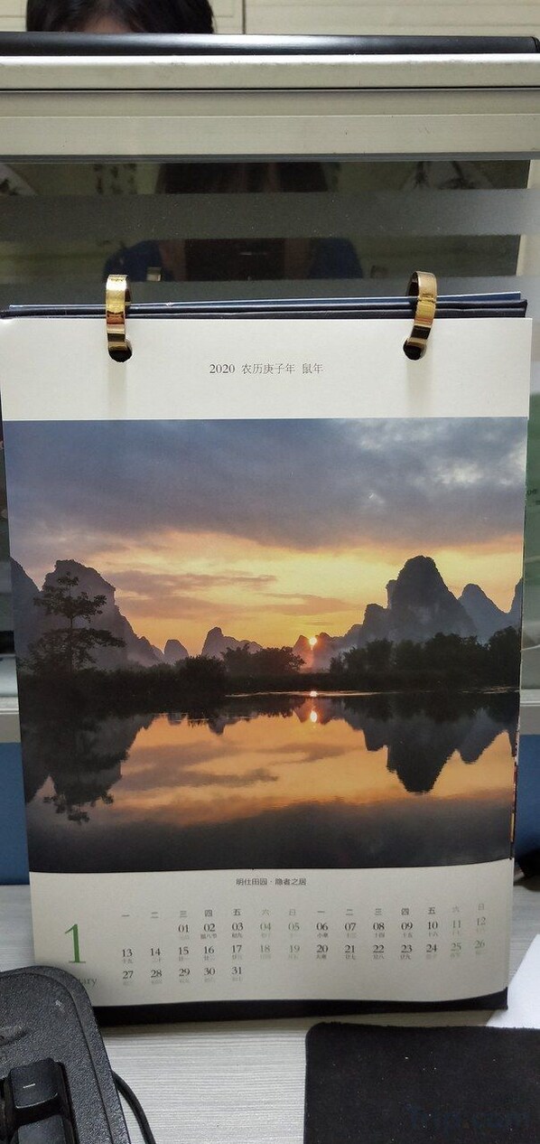 A calendar with a scenic landscape photo of mountains and a lake at sunset. - Daxin Mingshi Daoxiang Inn (Daxin)