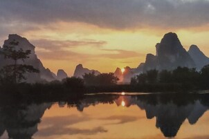 Un paisaje sereno con montañas reflejadas en aguas tranquilas durante el atardecer.