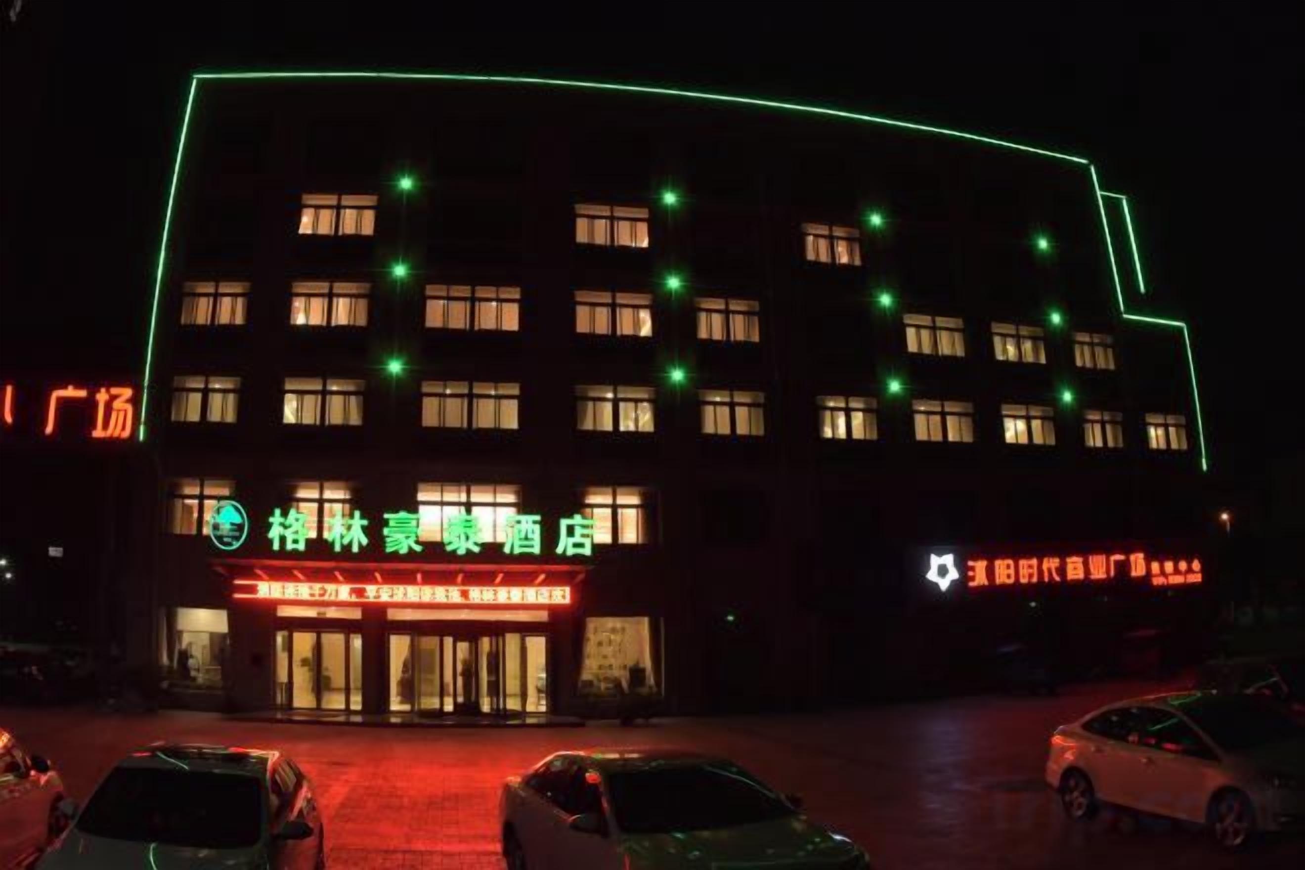 A building with multiple windows and a sign indicating a hotel. There are cars parked in front.